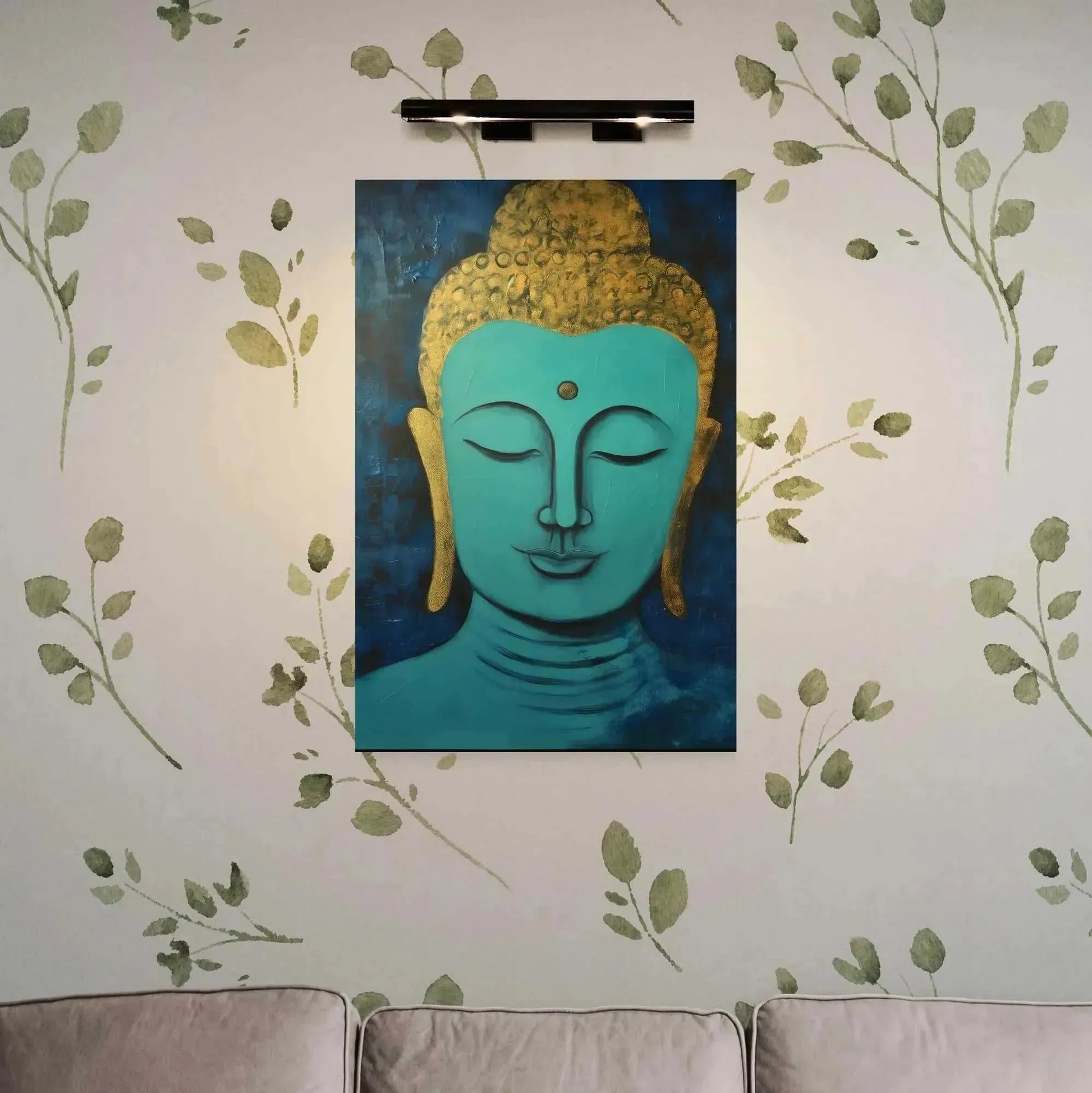 The "Tranquil Buddha Head Canvas" by Printify, a painting in calming shades of blue and gold that embodies the essence of Zen tranquility, is displayed on a wall with a leafy pattern. This artwork, titled "Buddha in Art Oregon," is subtly lit from above to enhance its peaceful ambiance. Beneath the painting sits a light-colored sofa.
